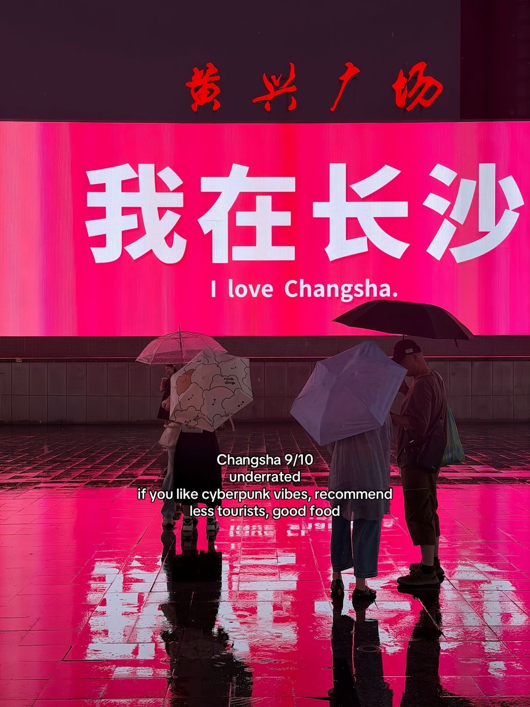 People with umbrellas beneath an I love Changsha sign
