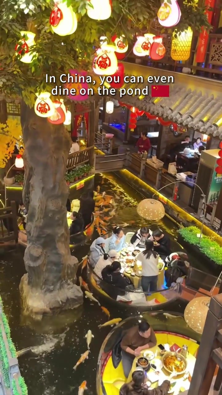 An overhead view of boat-shaped dining booths, traditional-style decor and koi-filled waterways