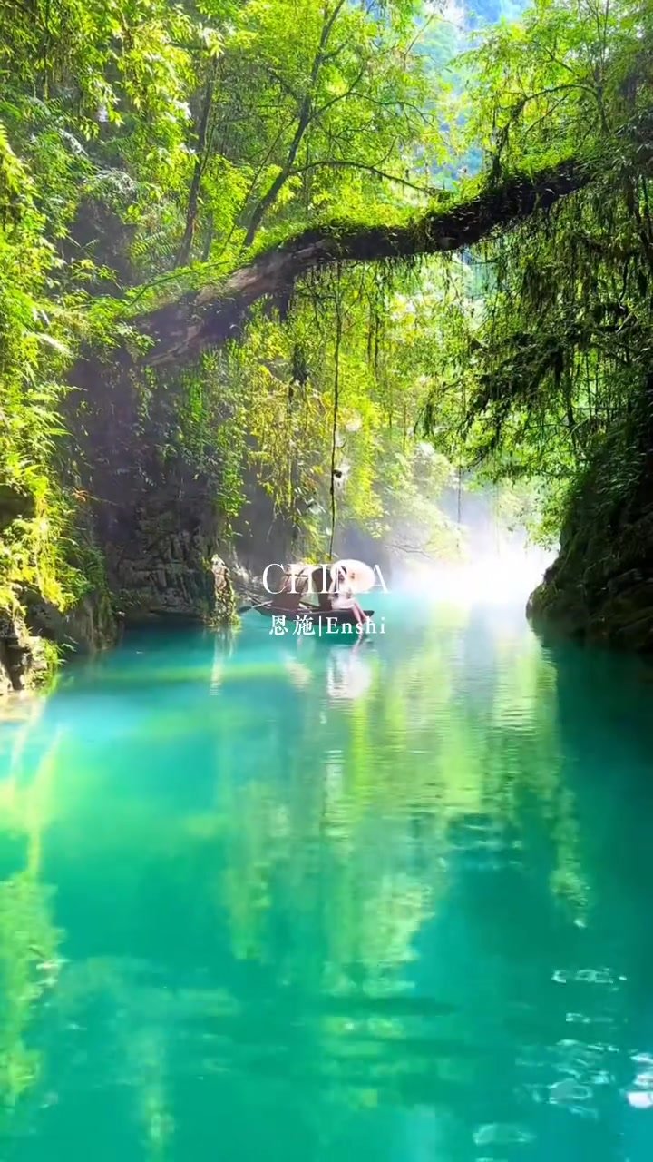 Sunlit turquoise water beneath dense forest in Pingshan Canyon