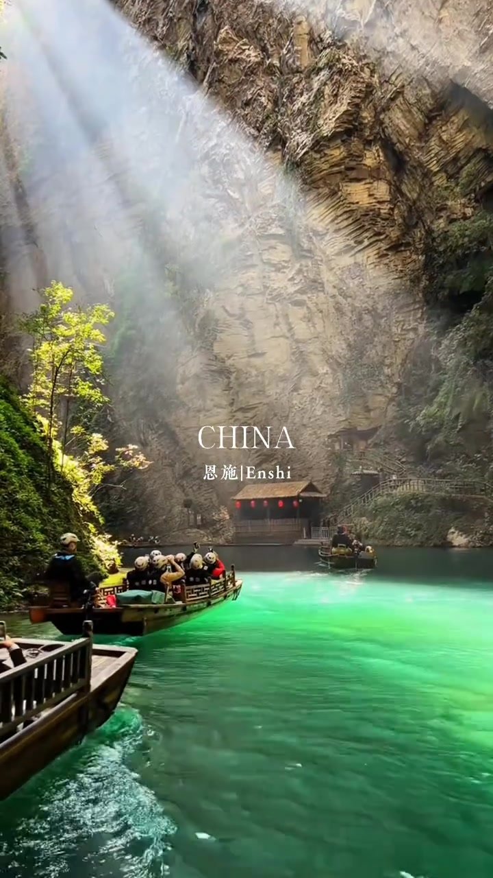 A beam of sunlight illuminating emerald water and sightseeing boats