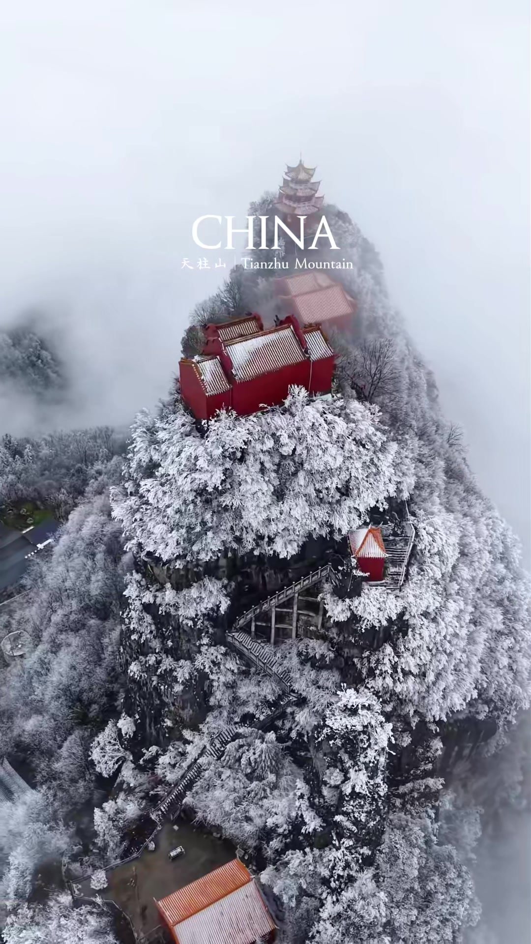 A red mountaintop building surrounded by snow and mist