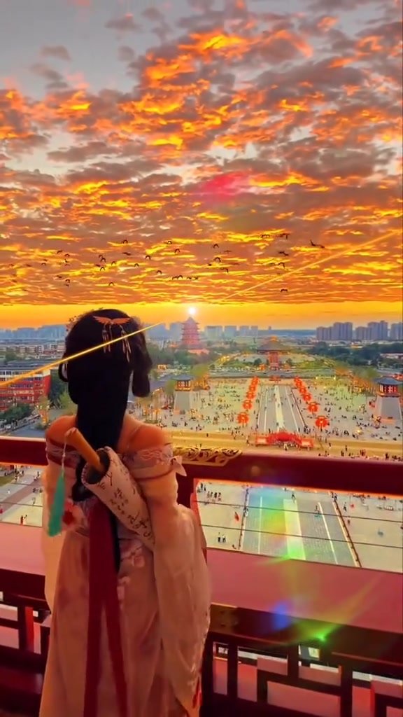 A traveler looking across Xi’an City Wall beneath a vivid orange sunset