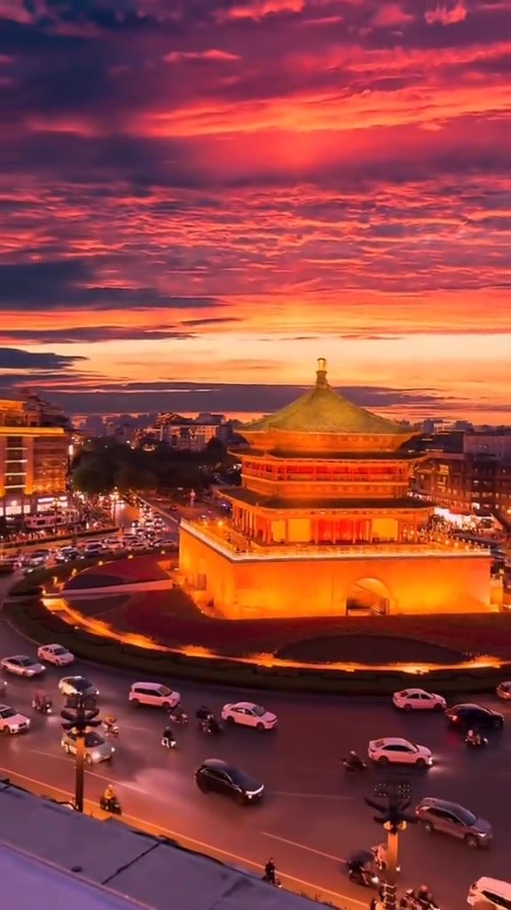 A glowing gate tower framed by a deep red evening sky