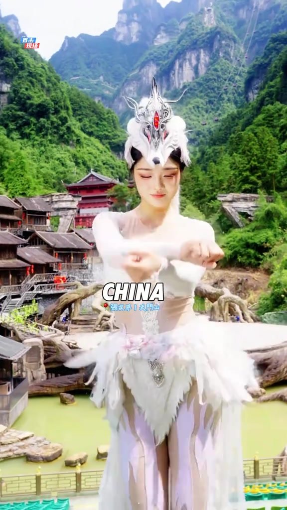 Fox-fairy performer holding a dance pose with Tianmen Mountain scenery behind her