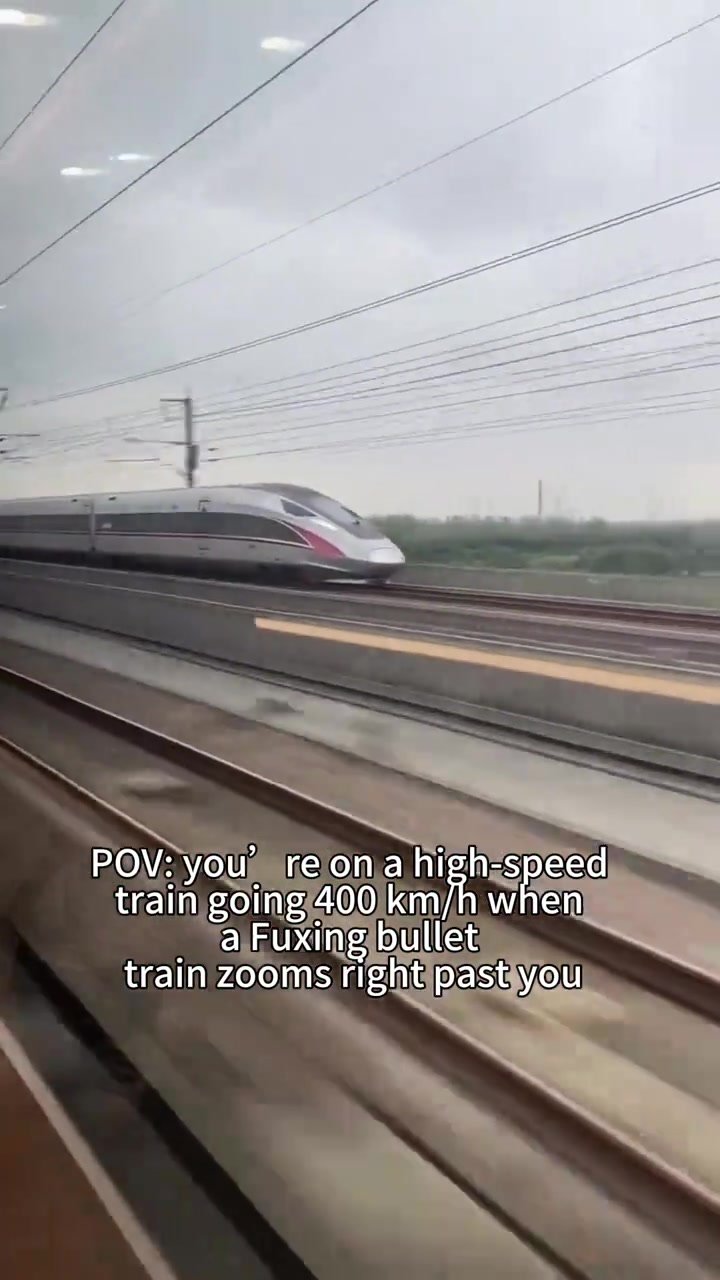 Streamlined Fuxing train seen through the window from a parallel railway line
